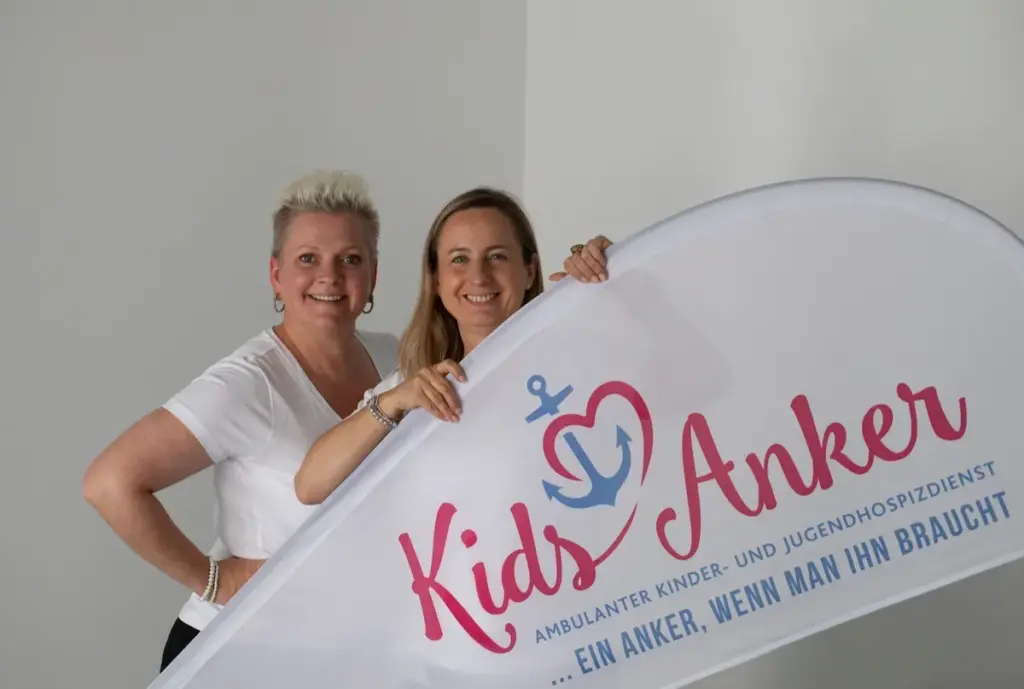 Zwei kidsanker mitarbeiter und dem logo als banner in der hand